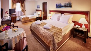 A hotel room with two beds, a TV, a desk with a lamp, and a painting on the wall. - Gunes Hotel Merter (Istanbul)