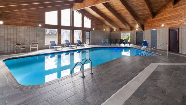 Una piscina interior con agua cristalina azul, vigas de techo de madera y paredes de azulejos.