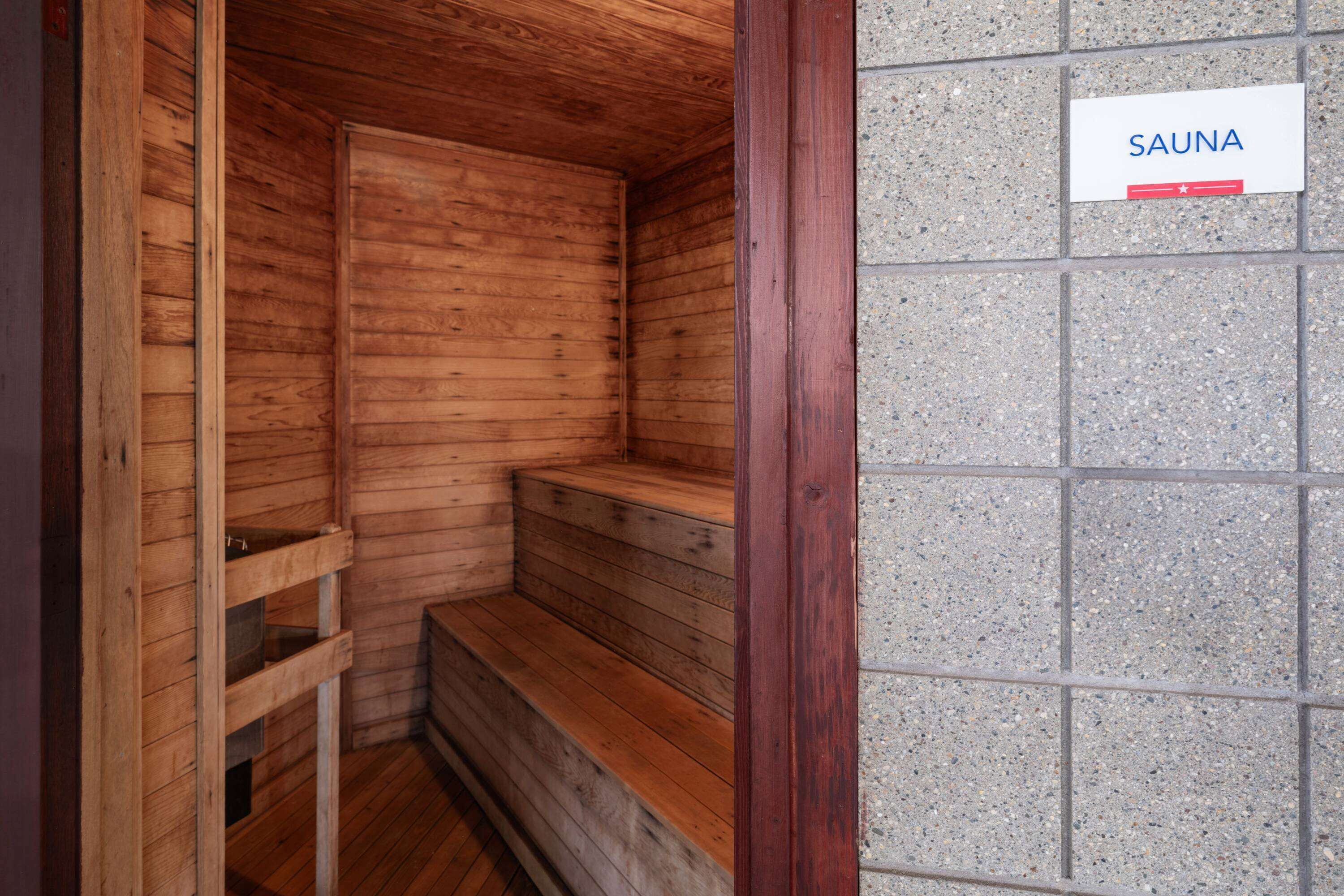 En sauna med træbænke og et skilt med teksten "SAUNA".