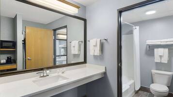 A bathroom with a large mirror, a sink, a toilet, and a shower.