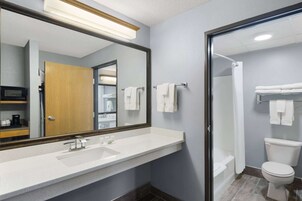 A bathroom with a large mirror, a sink, a toilet, and a shower.