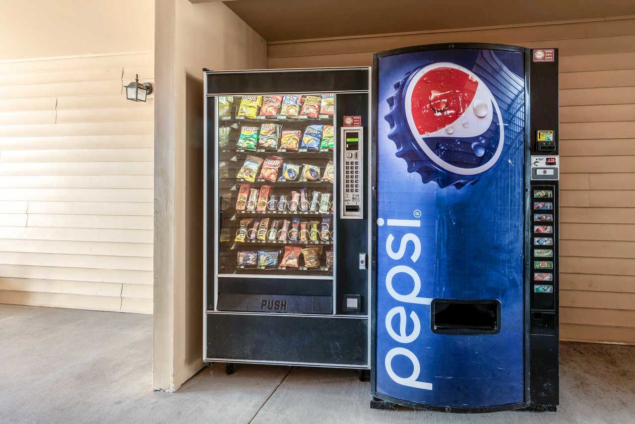 A Pepsi vending machine next to a building with a closed shutter.