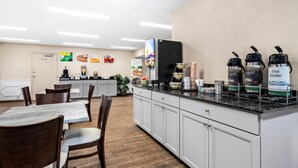 A clean, modern cafe with a long counter, seating area, and various food and drink options.