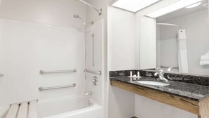 Une salle de bain moderne avec une baignoire blanche, un meuble-lavabo et un grand miroir.
