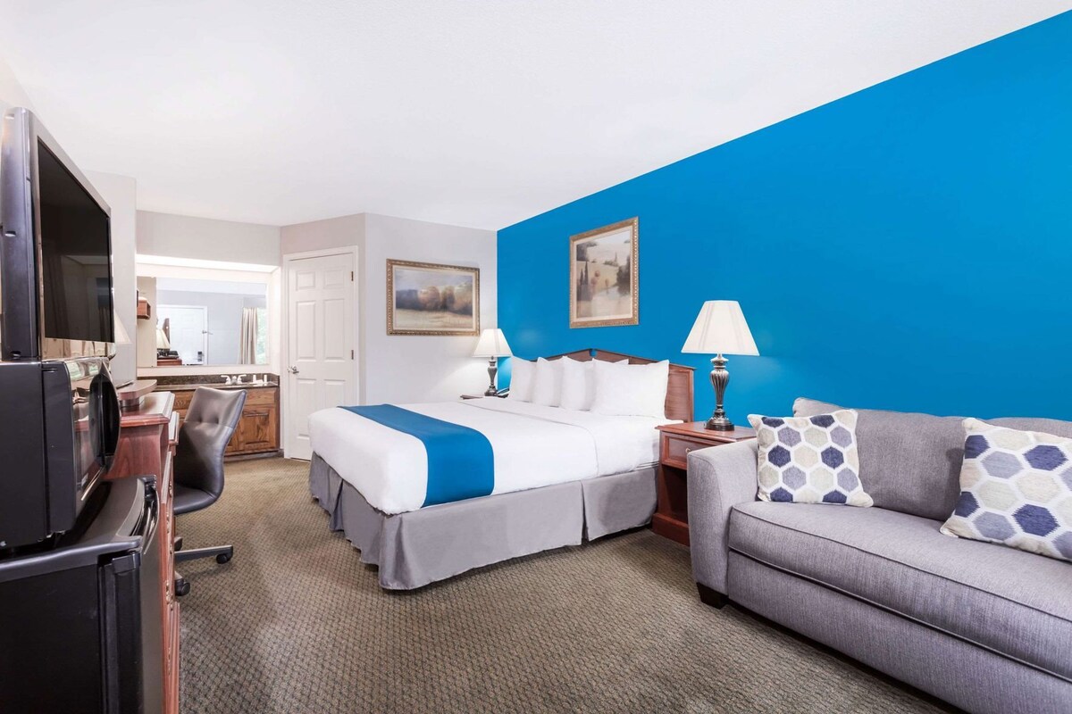 Ein Hotelzimmer mit einem Bett, einer Couch, einem Fernseher, einem Schreibtisch und einem Sessel.