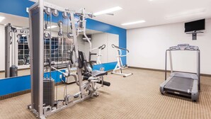 Une salle de sport équipée de machines de cardio, d’appareils de musculation et d’un tapis de course.