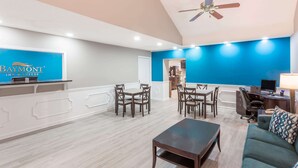 Un hall d’hôtel moderne comprenant un comptoir d’accueil, un espace repas et des sièges.