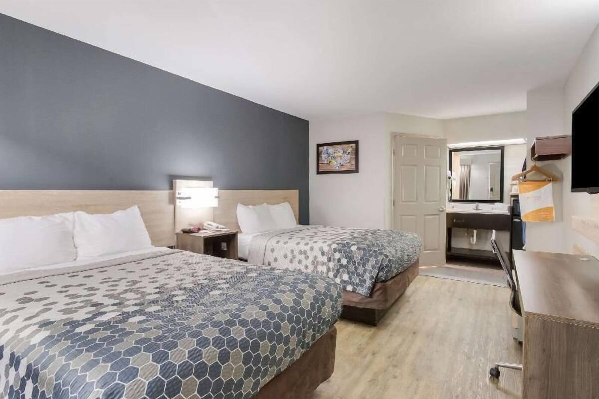 Habitación de hotel con dos camas, un escritorio, un espejo y una televisión.