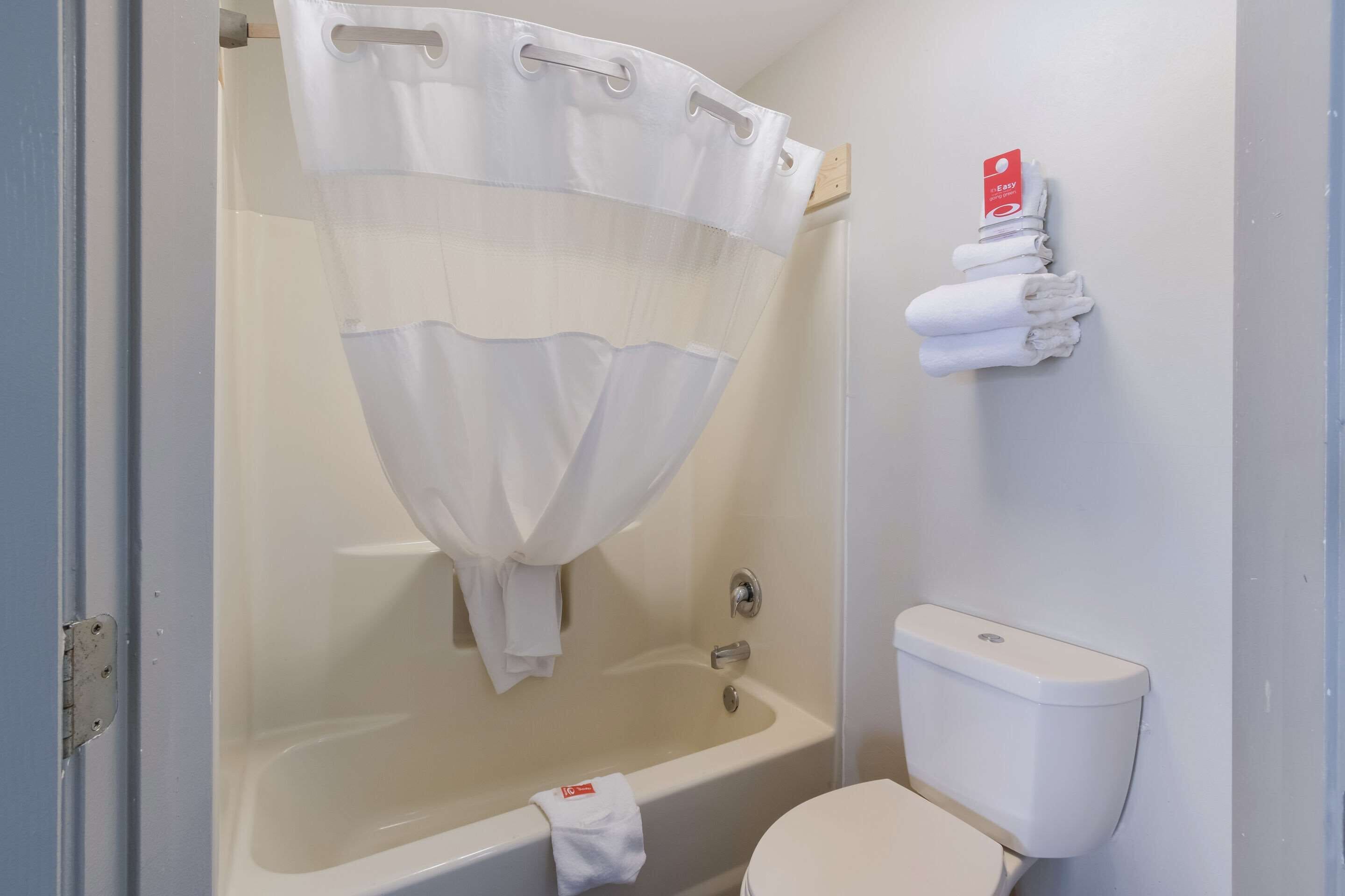 Un baño con bañera, inodoro y un perchero con toallas dobladas.