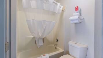 Un baño con bañera, inodoro y un perchero con toallas dobladas.