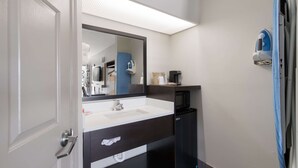 A modern bathroom with a white sink, dark vanity, and a large mirror. - Econo Lodge Greenville near University (Greenville)