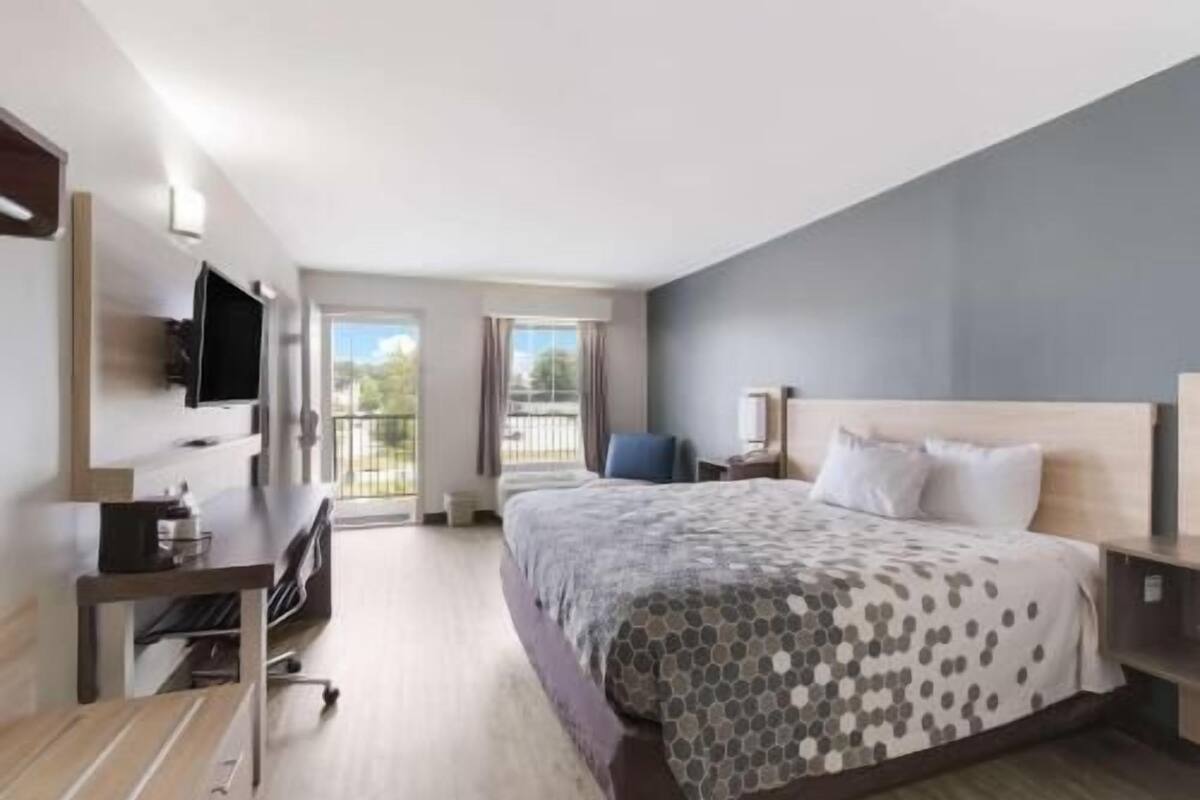 Ein Hotelzimmer mit Bett, Schreibtisch, Fernseher und Balkon.