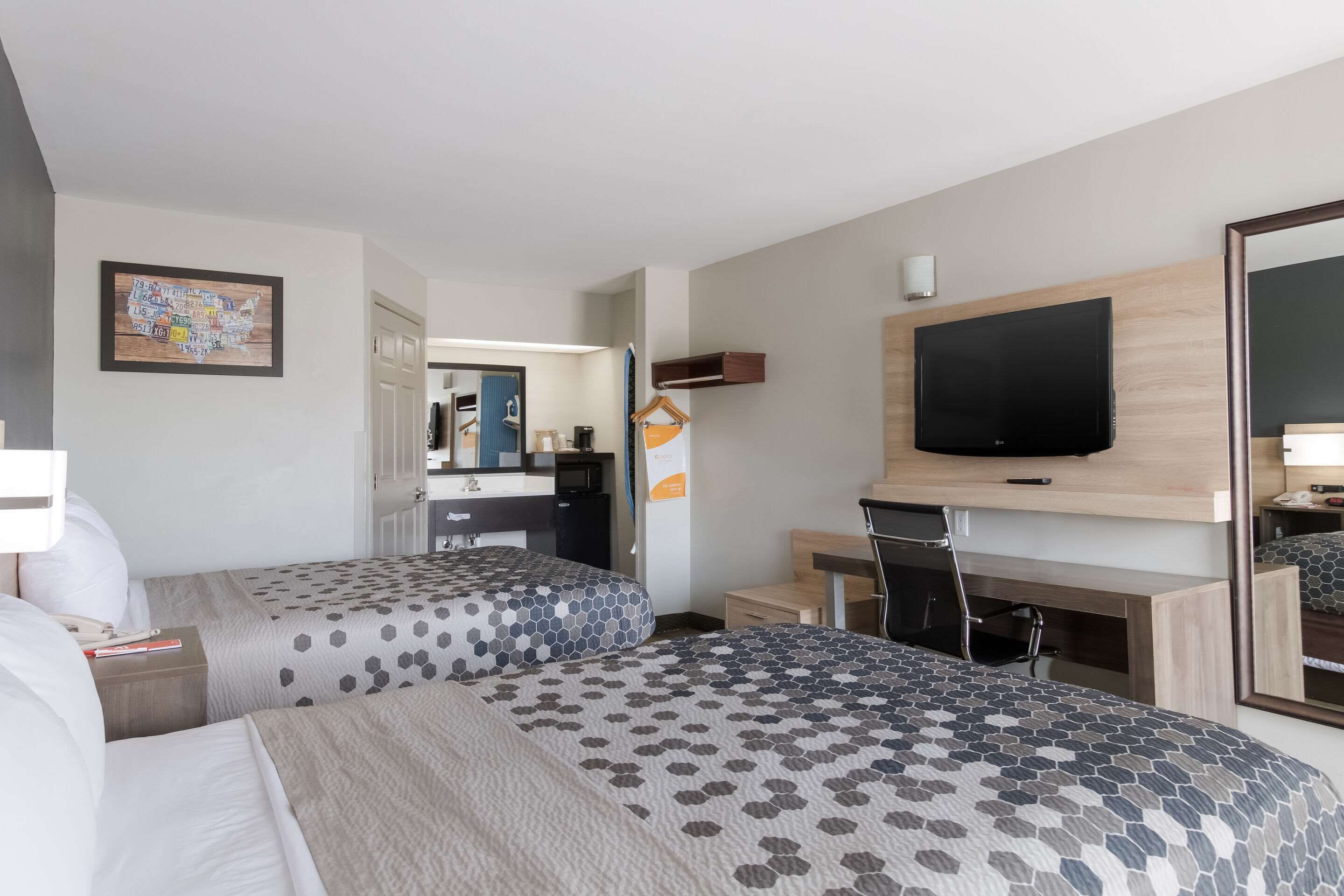 Une chambre d’hôtel avec deux lits, une télévision, un bureau et un miroir.