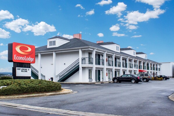 Een tweelaags EconoLodge gebouw met een bord, een trap en een parkeerplaats met meerdere auto's.