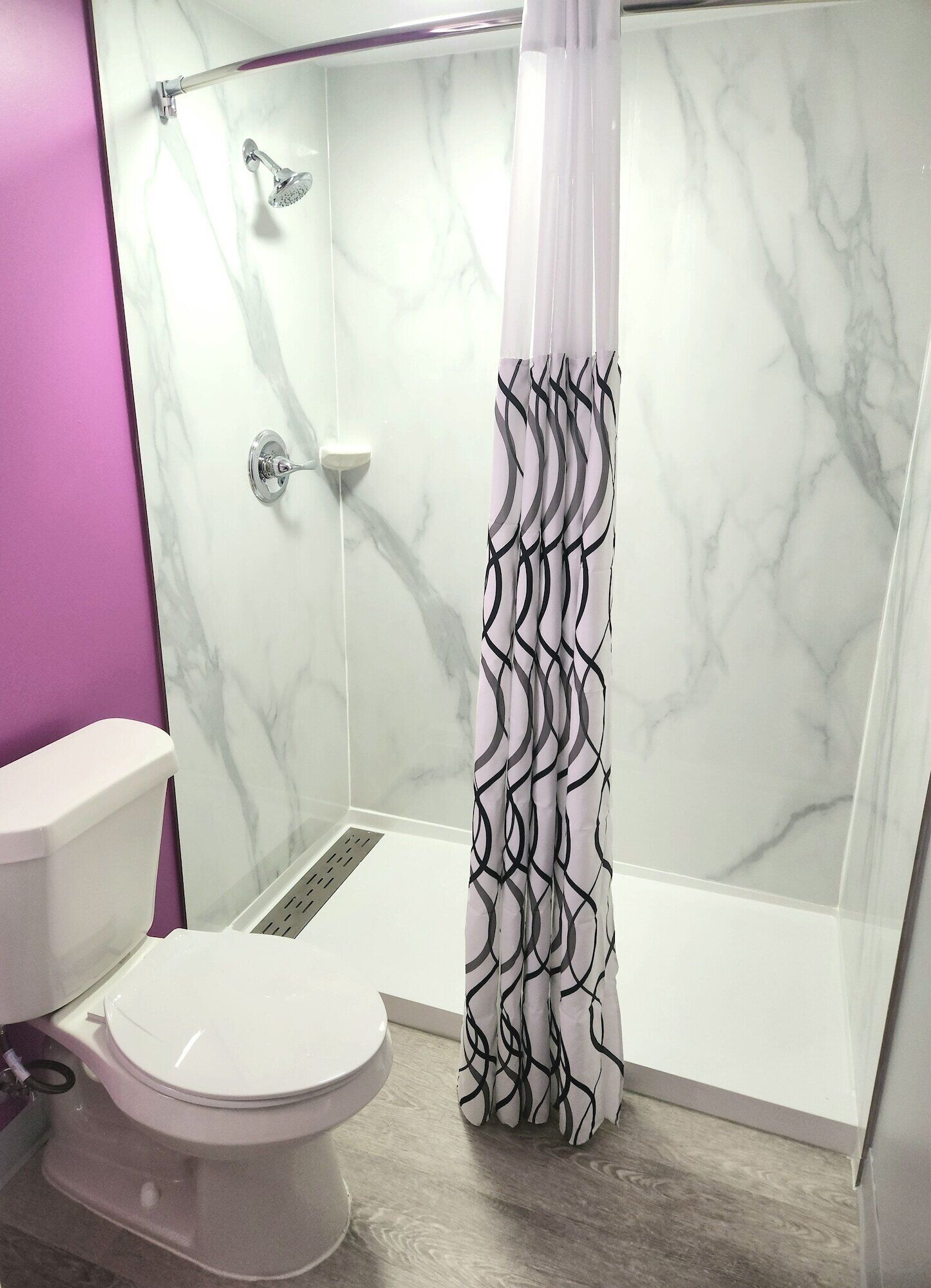 Un baño con ducha, inodoro y paredes de mármol.