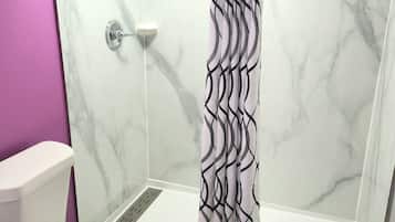 Un baño con ducha, inodoro y paredes de mármol.