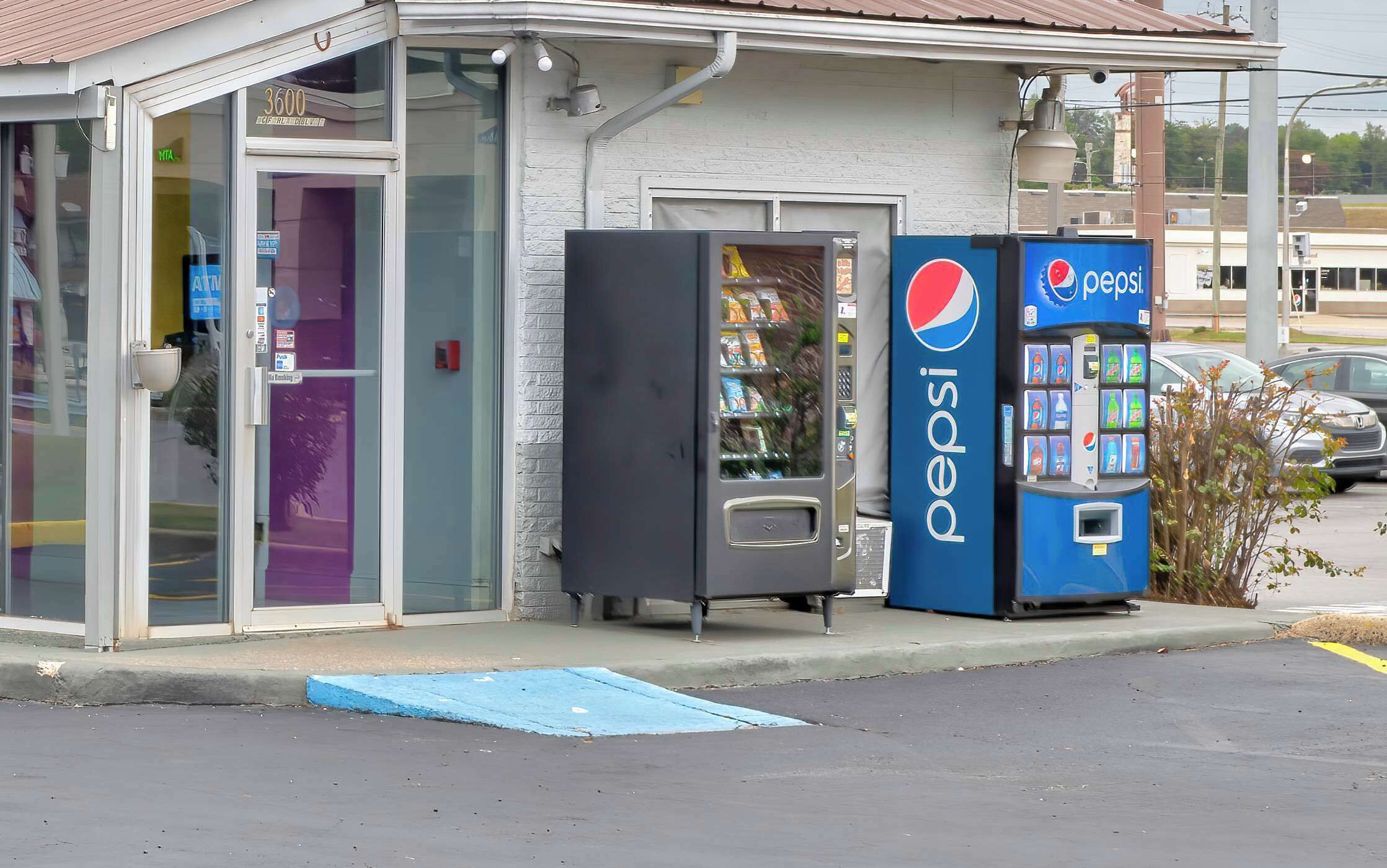 A building with a glass entrance, a Pepsi vending machine, and a refrigerator.
