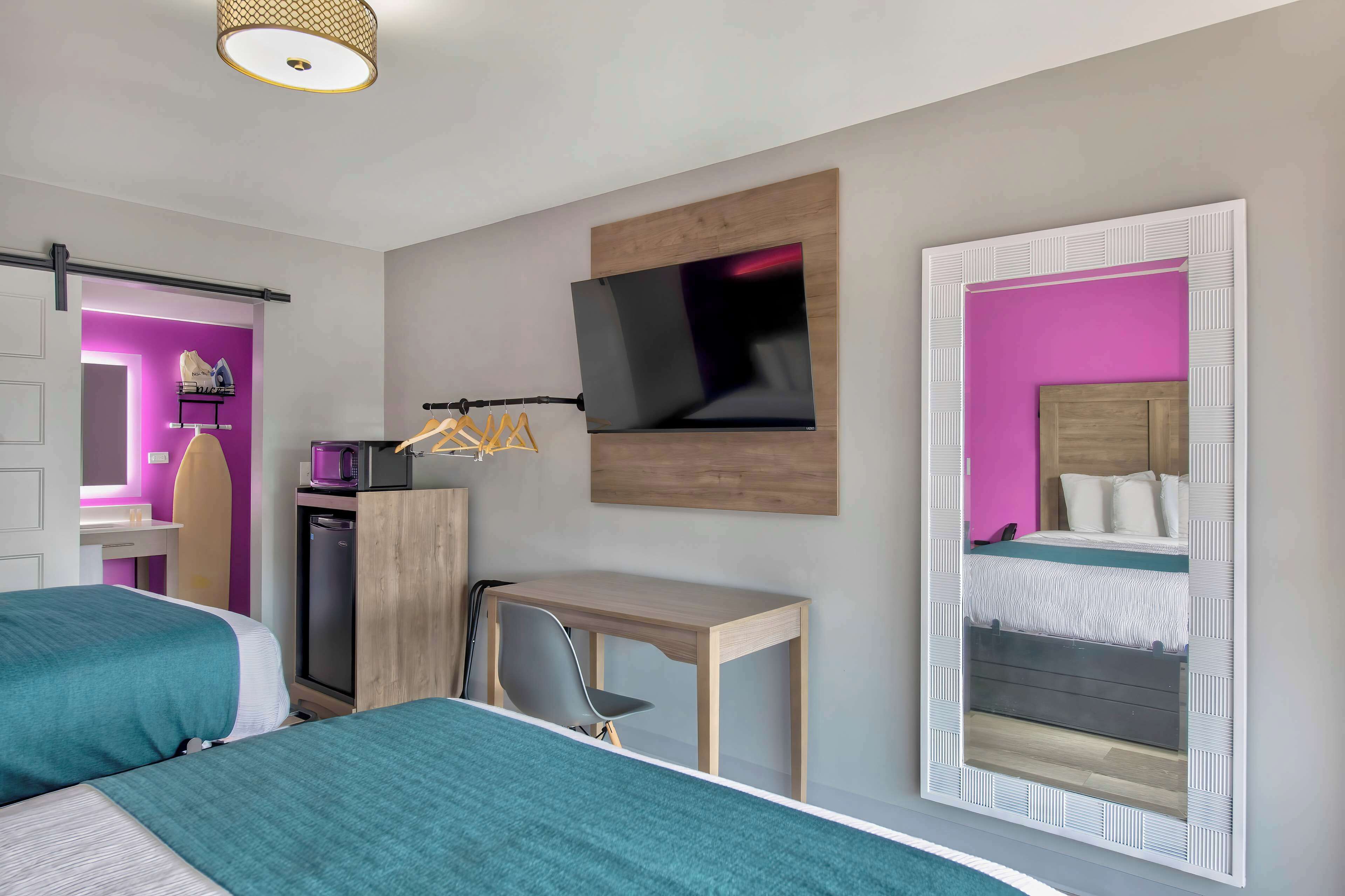 Habitación de hotel con dos camas, un escritorio, un televisor y un armario.