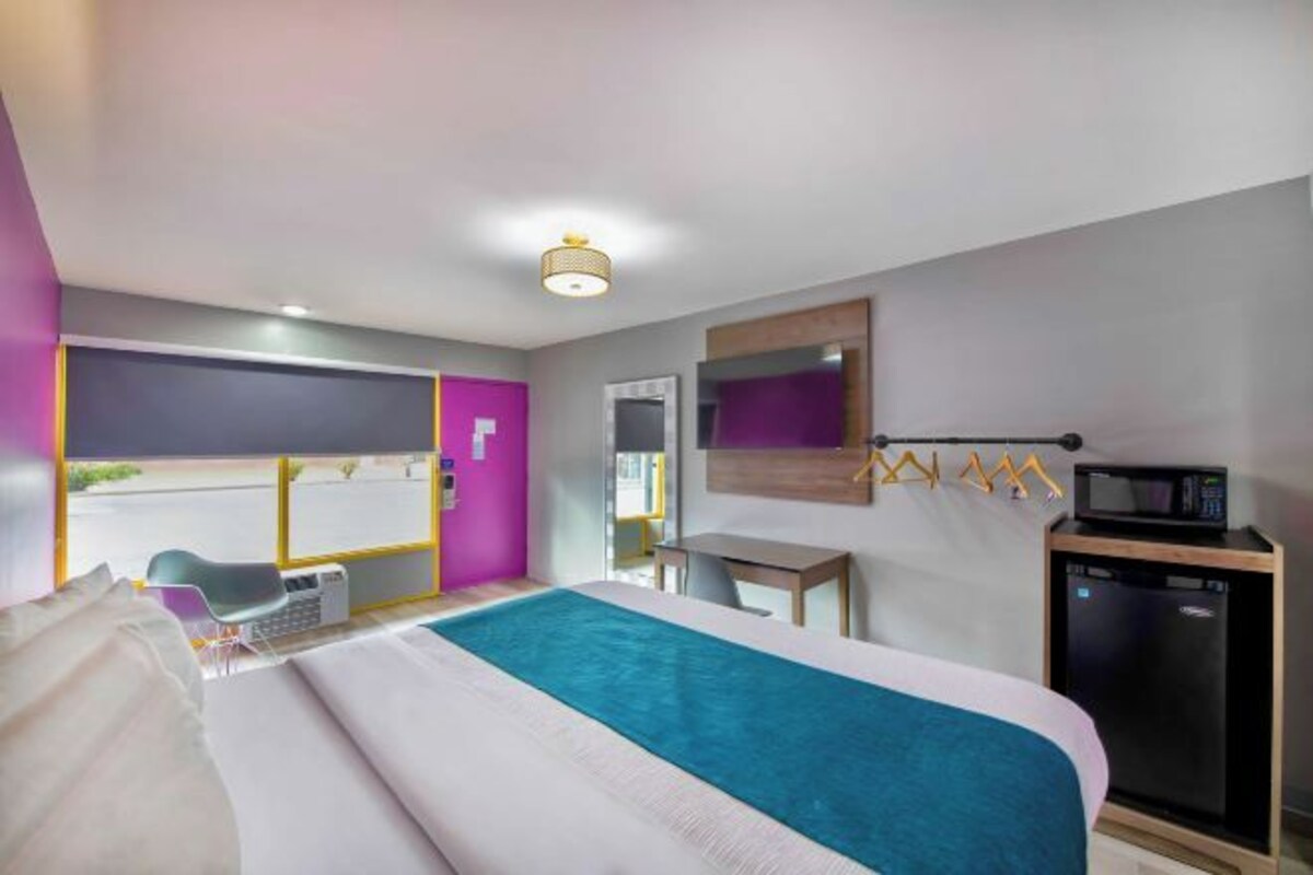Habitación de hotel con cama, escritorio, silla, microondas y ventana con vista a la calle.