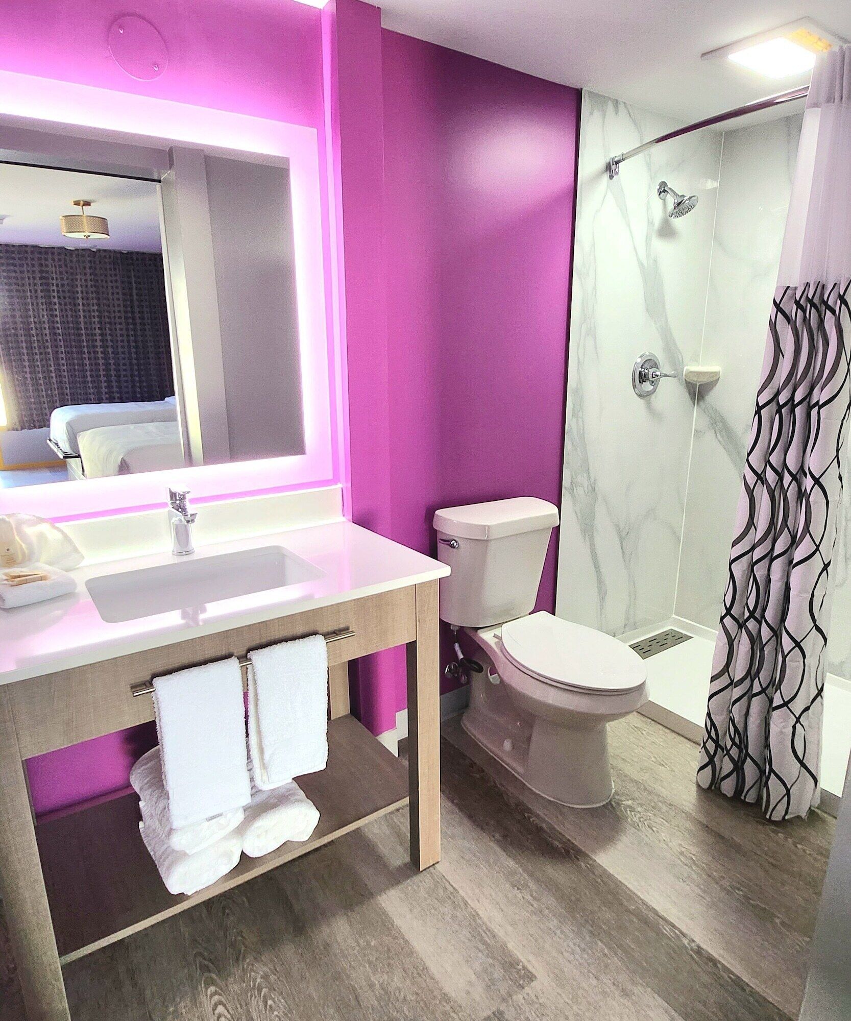 A modern bathroom with a marble sink, a toilet, and a shower.