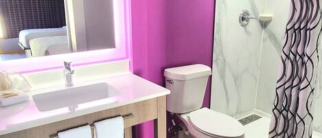 A modern bathroom with a marble sink, a toilet, and a shower.