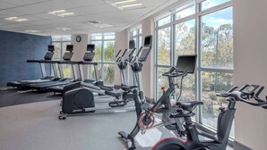 Et fitnessrum med løbebånd, crosstrainere og en ICG motionscykel, store vinduer og et ur på væggen.