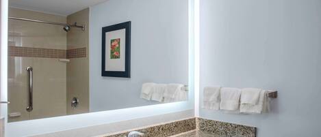 A bathroom with a granite countertop sink, a large mirror, a framed picture on the wall, and a towel rack with white towels.