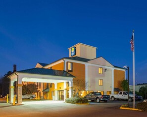A Comfort Inn hotel with a covered entrance, a parking lot, and an American flag.