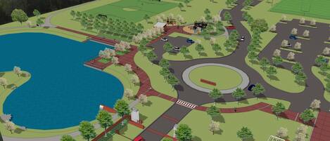 Un parque con un lago, senderos peatonales y un área de juegos.