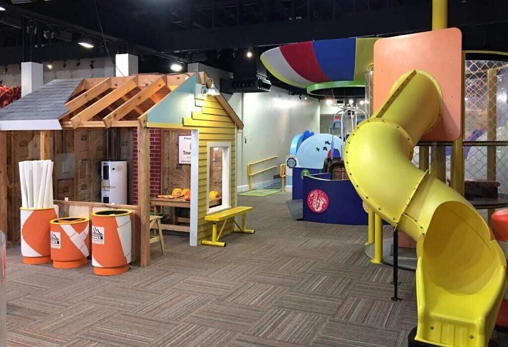 A children's play area with a slide, play structures, and storage bins.