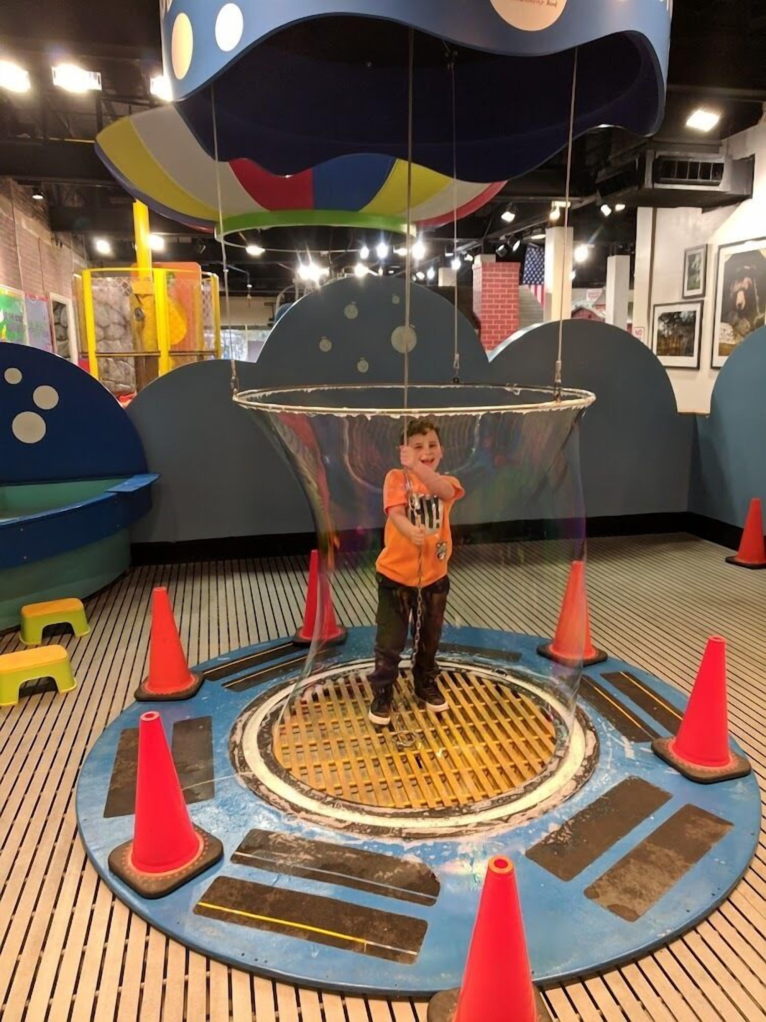 A child playing on a colorful, circular play structure with a hanging ring.