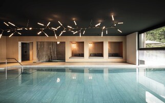 Una piscina techada, sombrillas, sillones reclinables de piscina