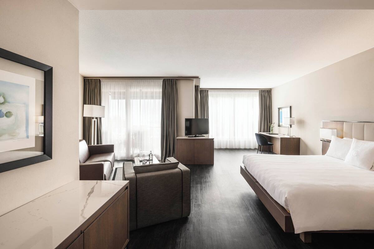 A hotel room with a bed, a desk, a TV, and a sofa.
