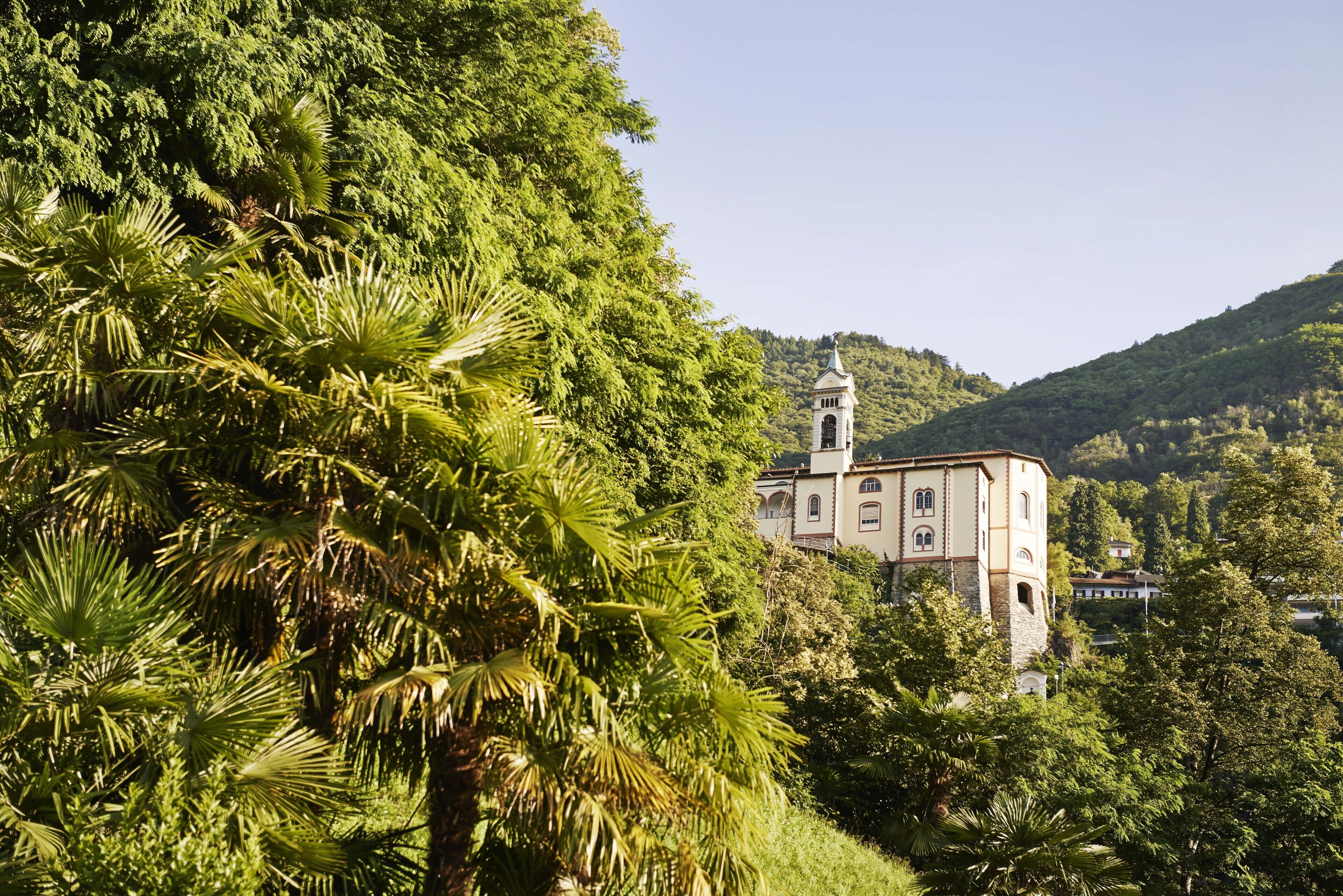 A building with a tower, surrounded by lush greenery and hills.
