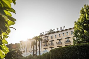 Un hotel de varios pisos con balcones y una vista despejada del entorno verde.