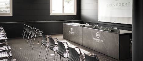 A conference room with a long table, chairs, and a presentation screen.