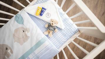 A crib with a checkered blanket, a teddy bear, and two baby products.