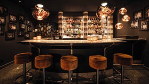 A bar area with a marble countertop, multiple liquor bottles, and framed pictures on the walls.