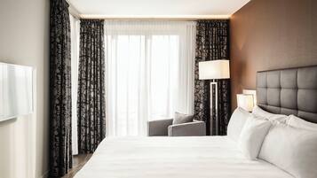 A hotel room with a large bed, a bedside table with a lamp, and a chair.