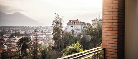 Un balcón con vistas a un paisaje urbano que incluye edificios, árboles y montañas a lo lejos.