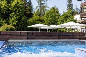 Relax by the serene pool surrounded by lush greenery and a wooden deck.
