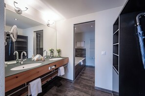 Bathroom features a dual sink vanity, large mirror, and glass-enclosed shower area.
