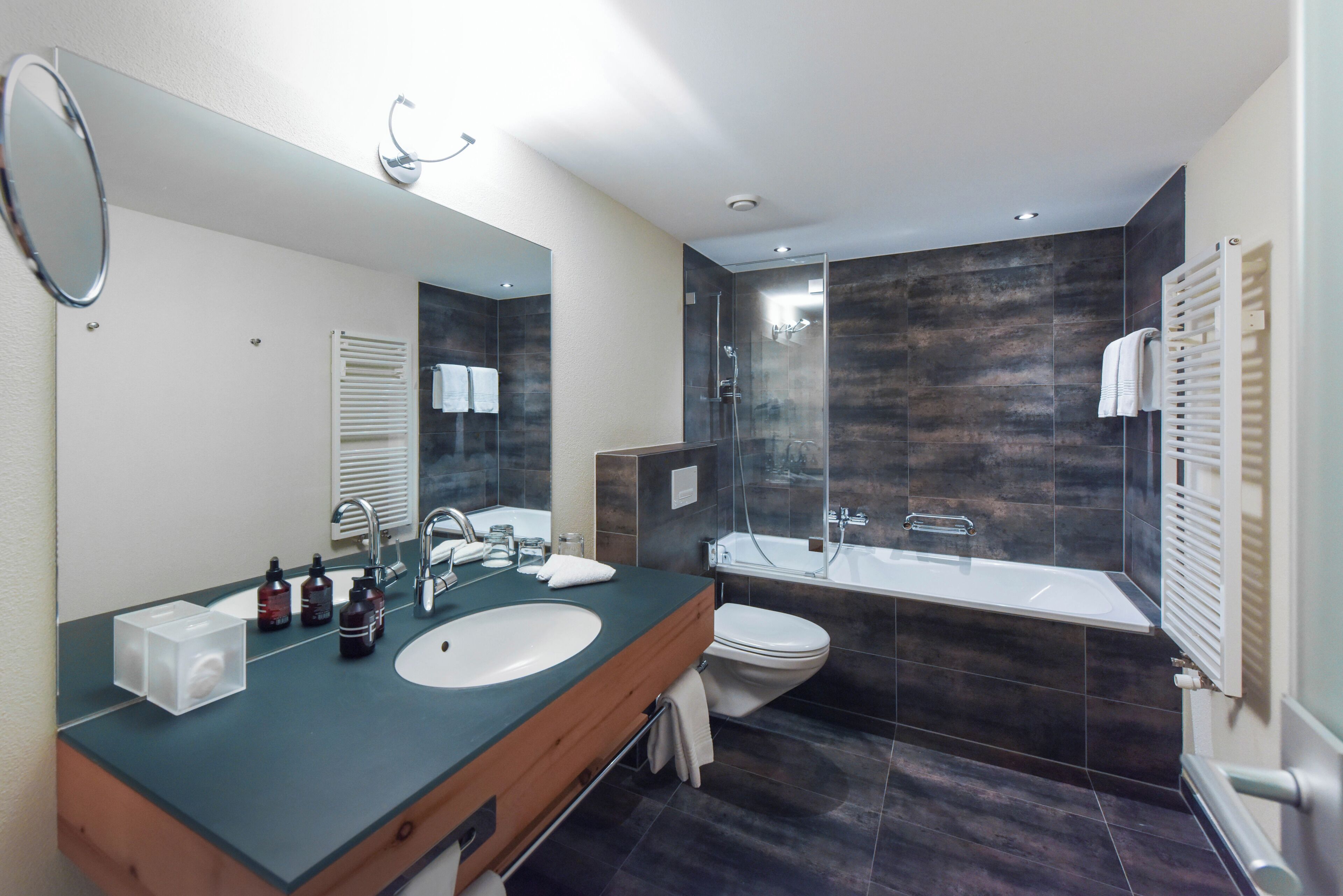 Un bagno moderno con uno specchio grande, un lavandino, un water e una vasca da bagno.