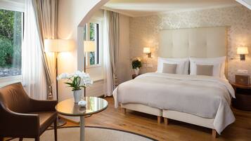 Une chambre d’hôtel avec un grand lit, un coin salon comprenant une chaise et une petite table, et une fenêtre avec des rideaux.