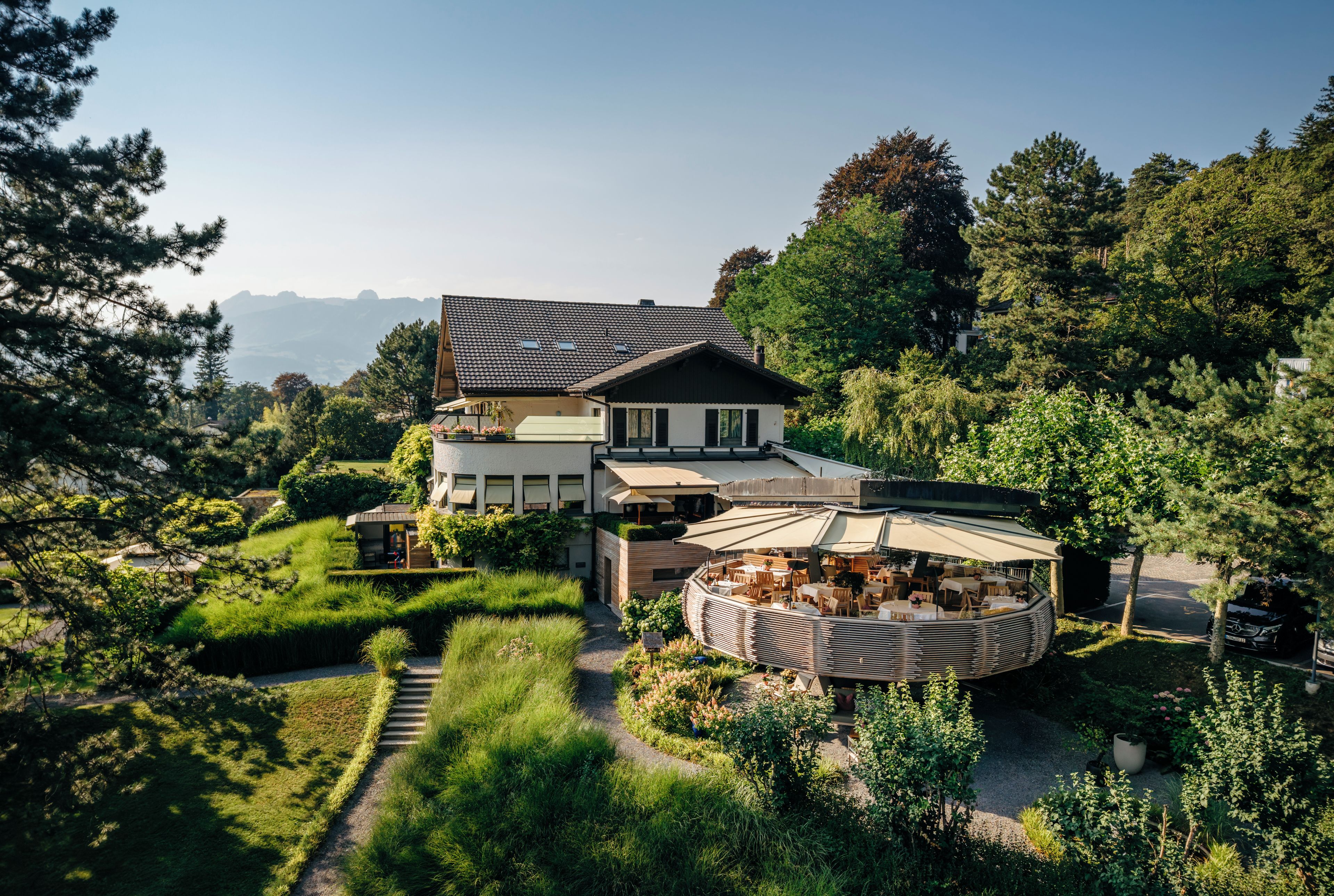 Ein zweistöckiges Haus mit einer Terrassenfläche und Blick auf die umliegende Landschaft.