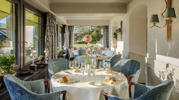 Un comedor con una mesa dispuesta para seis personas, sillas tapizadas en azul y vistas al exterior.