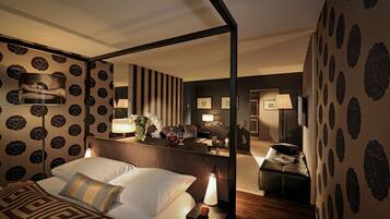 A hotel room with a bed, bedside table, lamp, and a mirror reflecting the room.