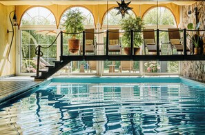 A pool with a glass bottom, surrounded by a deck with chairs and potted plants.