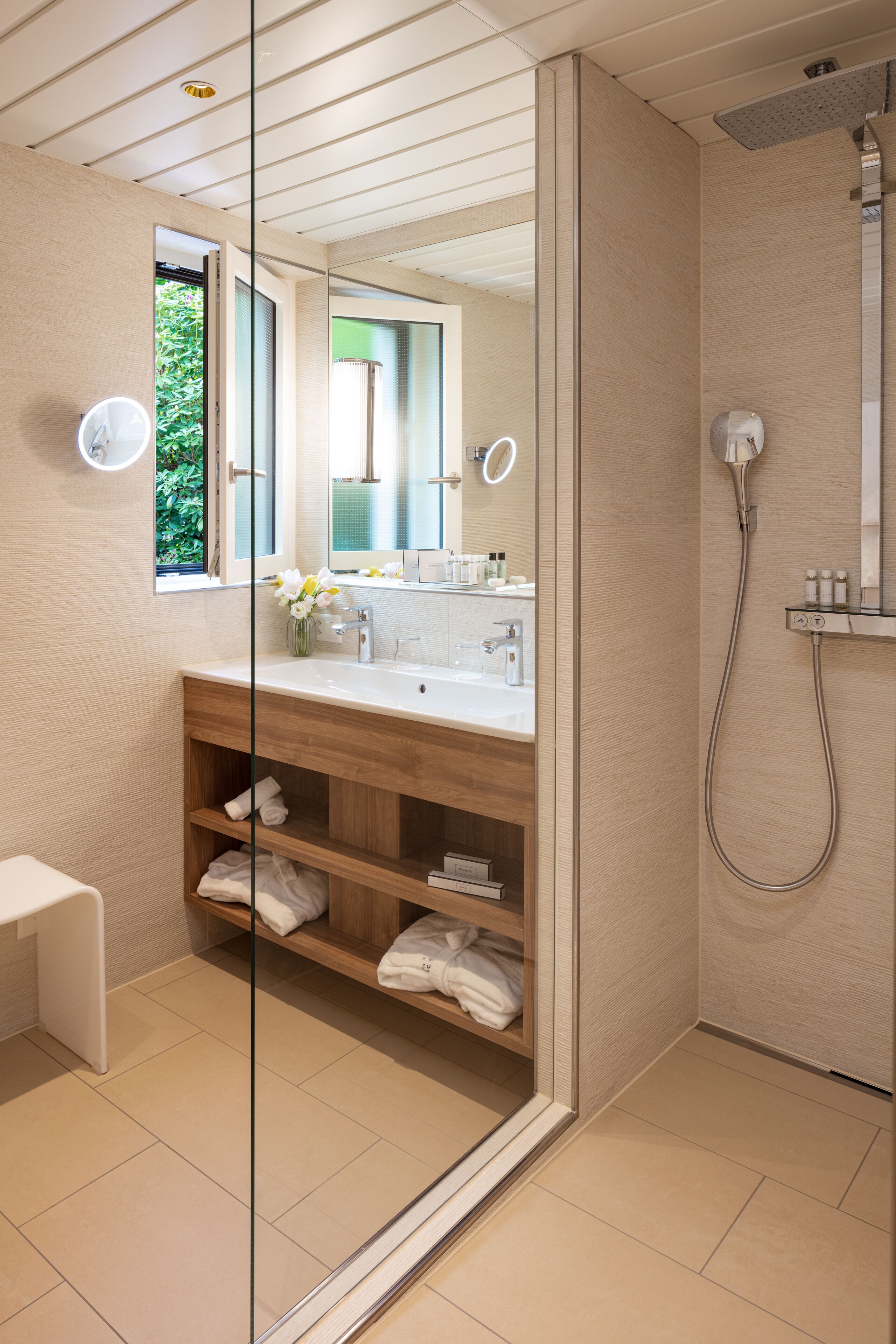Une salle de bain moderne avec une douche à parois de verre, un meuble-lavabo en bois et un grand miroir.