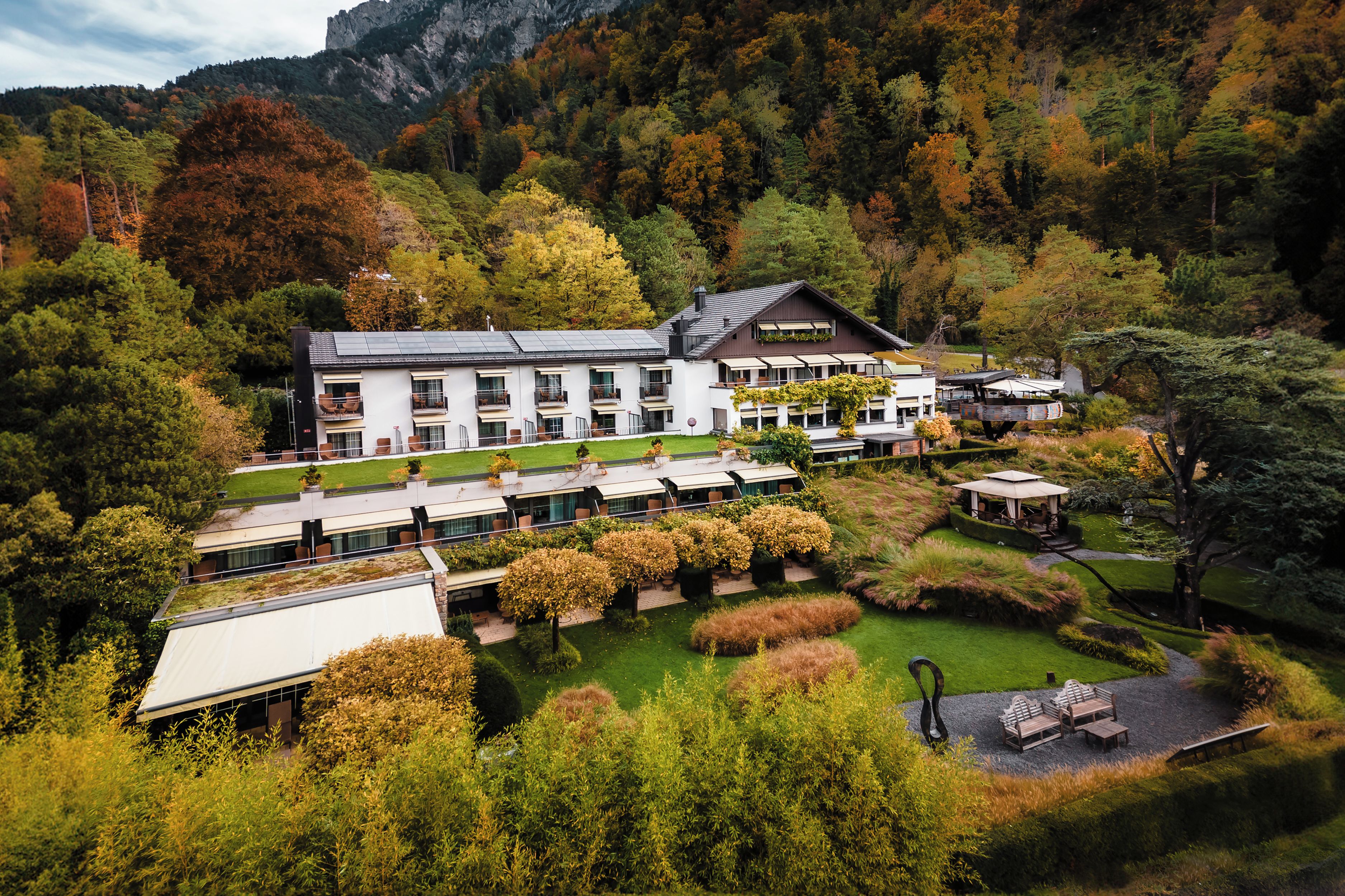 Un hotel moderno con varios pisos, asientos al aire libre y un jardín.